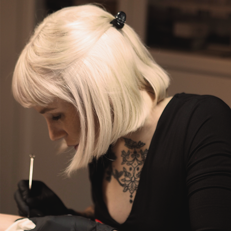 Ein Foto von Mona Hozzel der Geschäftsführerin von Heart and Poke, während sie Sommersprossen Tattoos sticht, von links fotografiert.