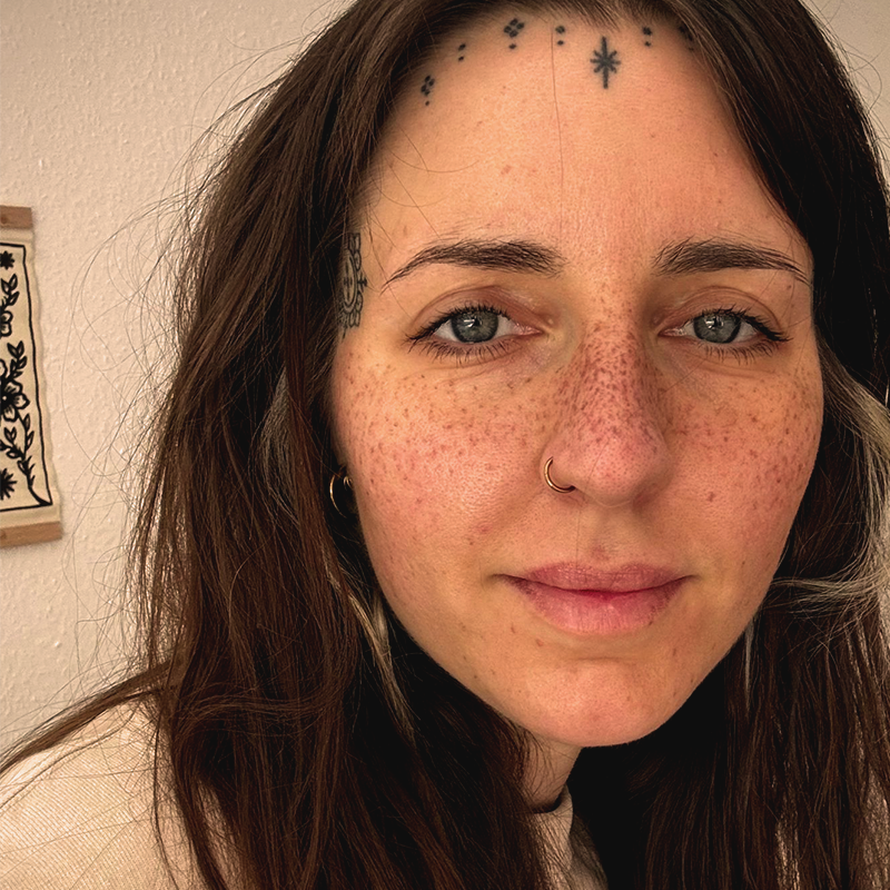 Man sieht eine Nahaufnahme von einem Frauengesicht von Sommersprossen Tattoos.