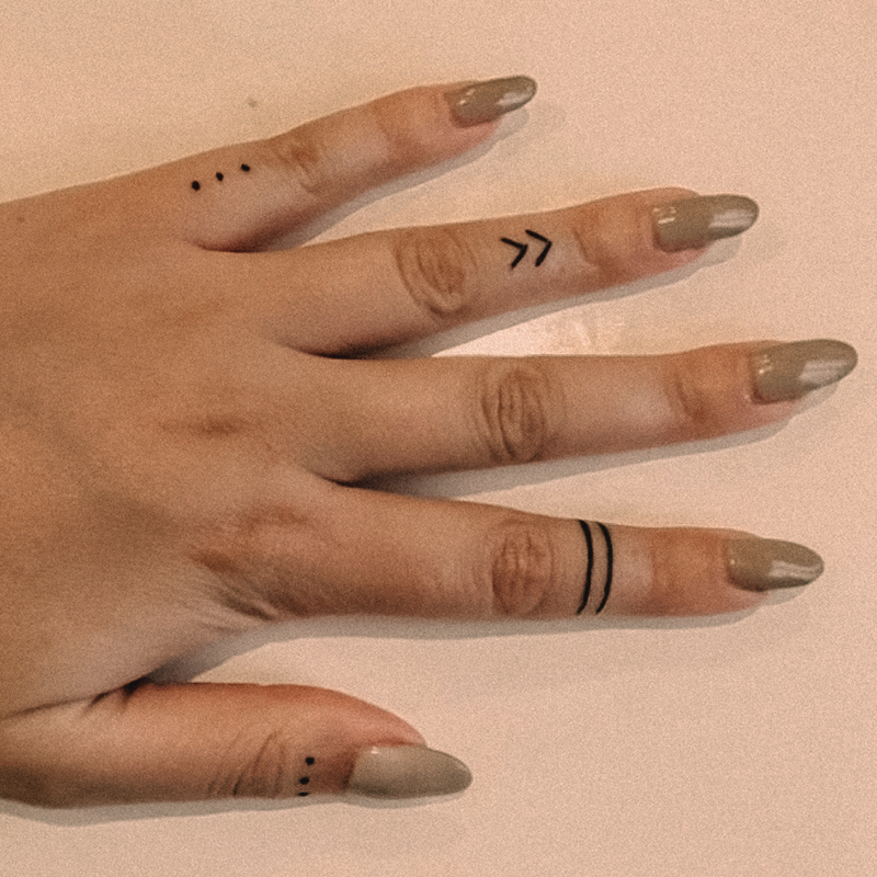 Man sieht eine Hand einer Frau mit einem Outline Handpoke Tattoo